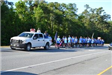 Group running behind white police truck