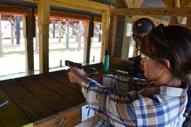 Woman wearing plaid shirt shooting handgun