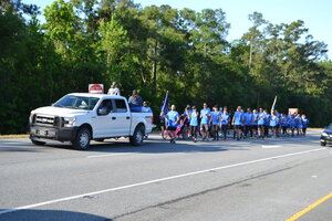 Group running behind white police truck